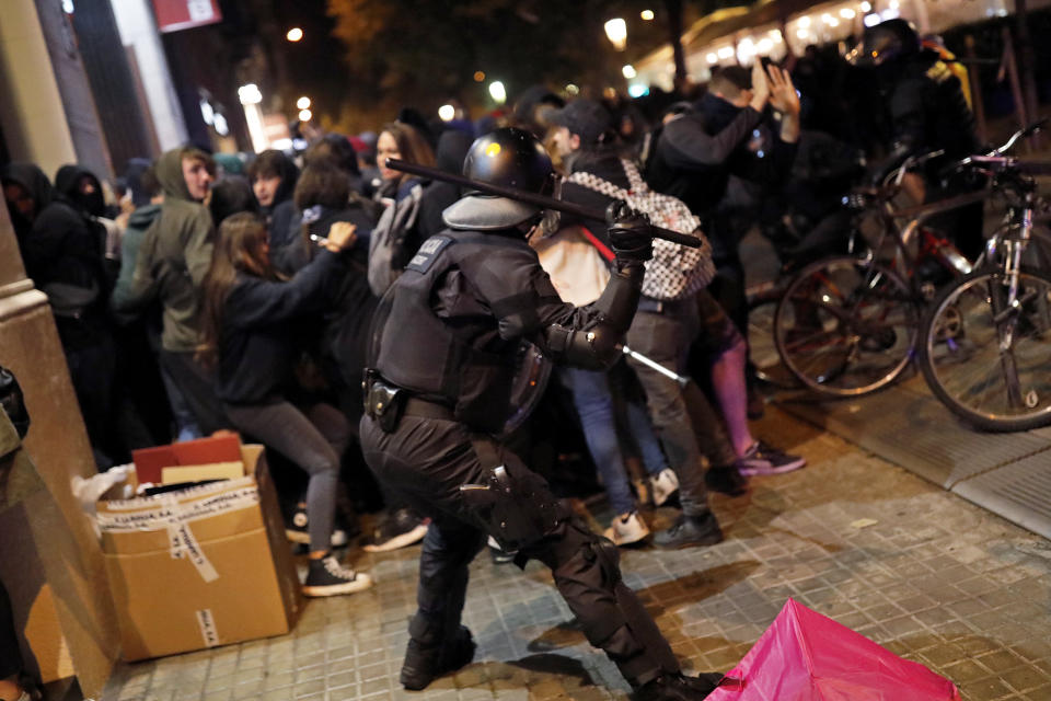 A policeman uses his baton again pro-independence demonstrators in Barcelona, Spain, Thursday, Oct. 17, 2019. Catalonia's separatist leader vowed Thursday to hold a new vote to secede from Spain in less than two years as the embattled northeastern region grapples with a wave of violence that has tarnished a movement proud of its peaceful activism. (AP Photo/Bernat Armangue)