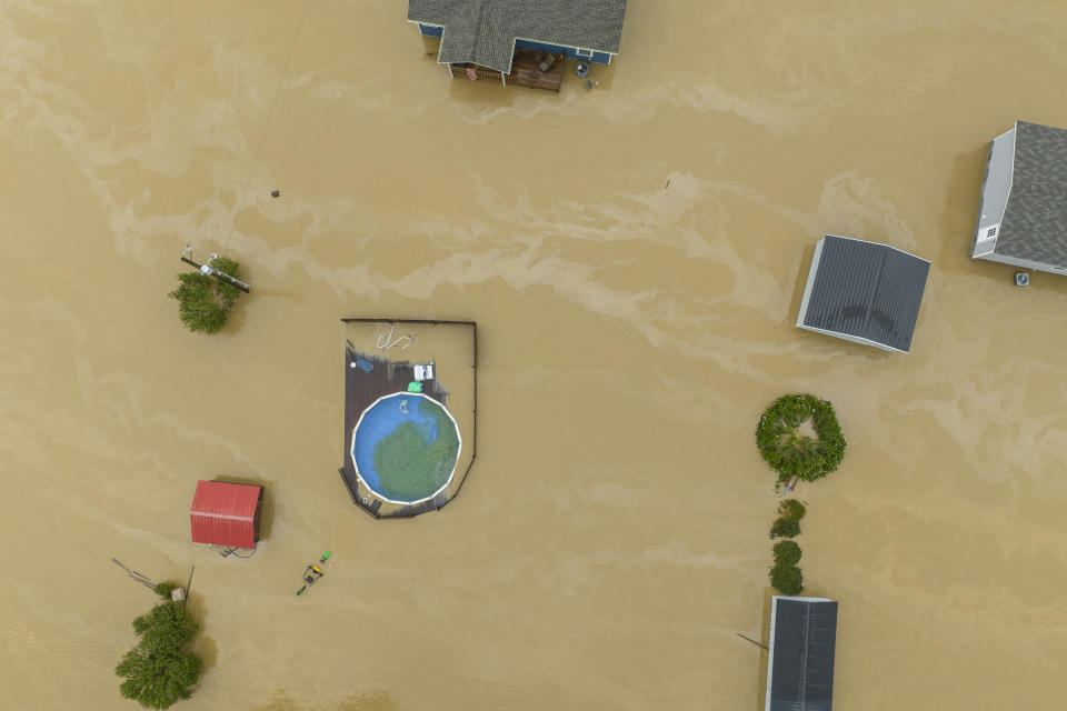 An aerial view of flooded homes and structures, with a few trees poking above the muddy waters.