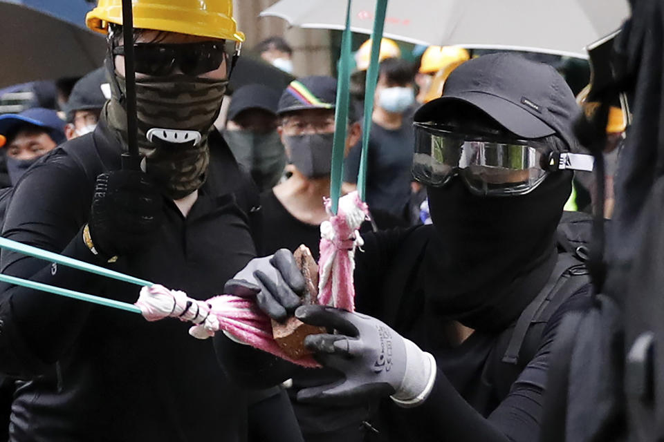 Protesters use a homemade sling shot to shoot bricks to the Tseung Kwan O police station during an anti-extradition bill protest in Hong Kong, Sunday, Aug. 4, 2019. Protesters held two more rallies Sunday after Hong Kong police announced more than 20 people were arrested following clashes at an earlier demonstration, adding to increasingly tense confrontations with the Chinese territory's government. (AP Photo/Vincent Thian)