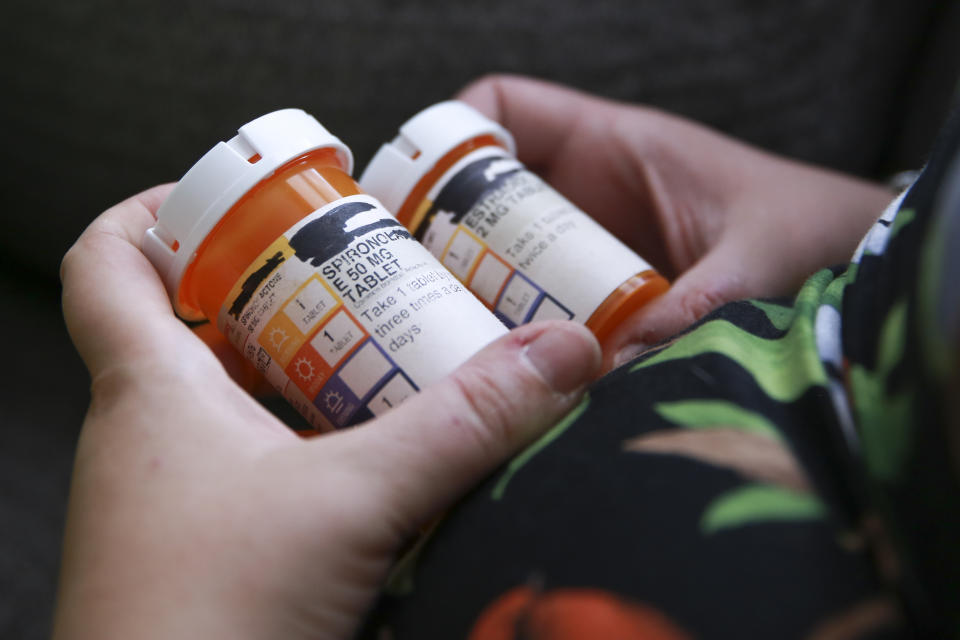 Sage Chelf holds bottles of medications for hormone replacement therapy as part of her gender affirming care as a trans woman at home in Orlando Fla., May 27, 2023. Chelf began making plans to leave the state after Florida legislation caused her to lose access to gender affirming care. (AP Photo/Laura Bargfeld)