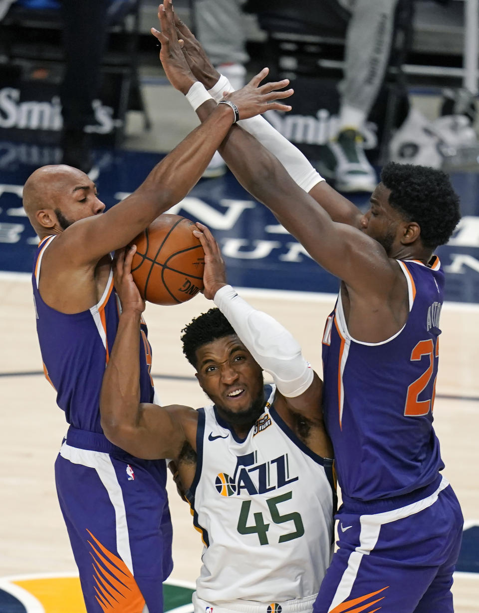 Phoenix Suns' Jevon Carter, left, and Deandre Ayton, right, defend against Utah Jazz guard Donovan Mitchell (45) during the first half of an NBA preseason basketball game Saturday, Dec. 12, 2020, in Salt Lake City. (AP Photo/Rick Bowmer)