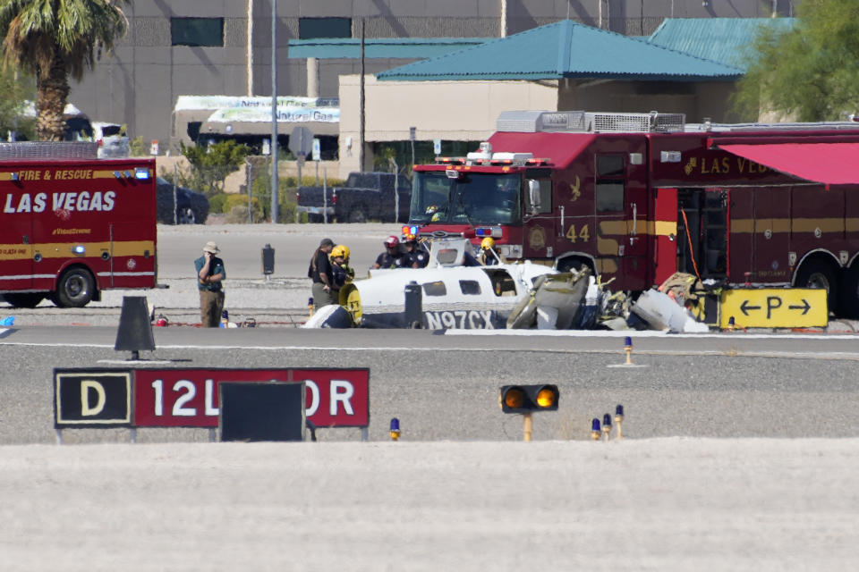 Officials investigate the wreckage of a plane at the site of a fatal crash at the North Las Vegas Airport, Sunday, July 17, 2022, in North Las Vegas, Nev. Authorities say several people are dead after two small planes collided at North Las Vegas Airport. (AP Photo/John Locher)