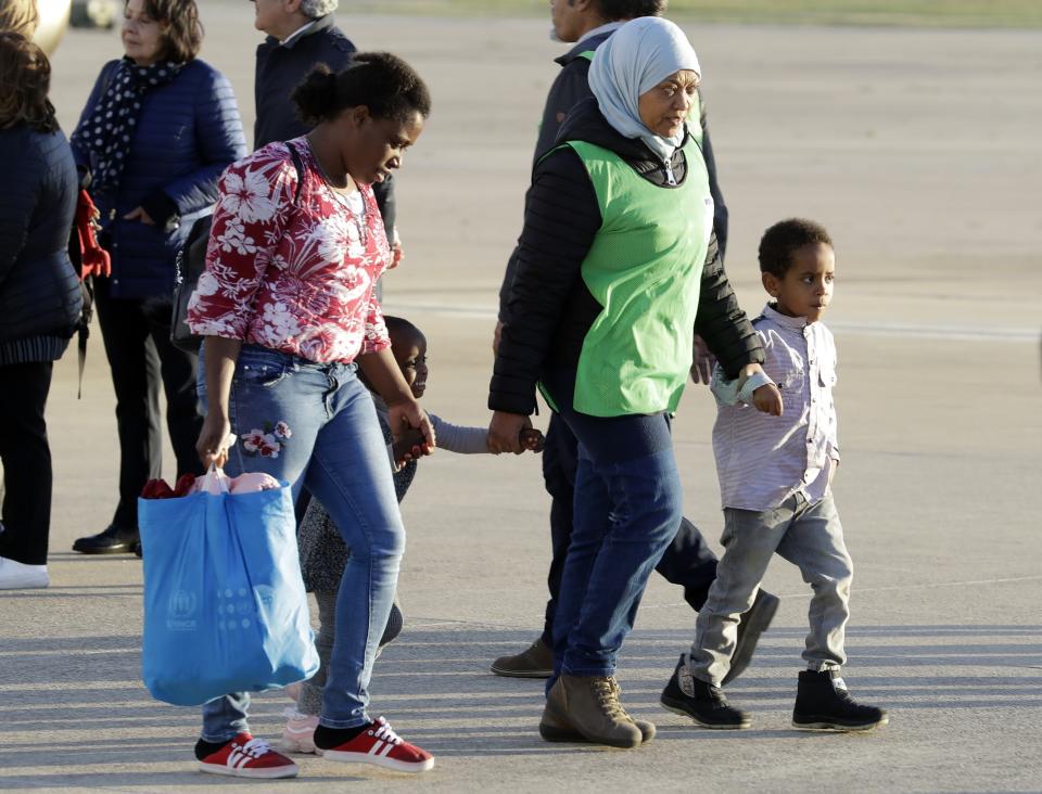 A woman and two children are assisted by UNHCR (United Nations Refugee Agency) personnel, second from right, after disembarking from an Italian military aircraft arriving from Misrata, Libya, at Pratica di Mare military airport, near Rome, Monday, April 29, 2019. Italy organized a humanitarian evacuation airlift for a group of 147 asylum seekers from Ethiopia, Eritrea, Somalia, Sudan and Syria. (AP Photo/Andrew Medichini)