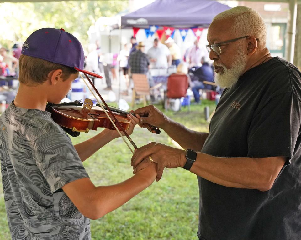 River Raisin Ragtime Revue music director emeritus William Hayes of Ypsilanti, right, shows Nick Baty, then 11, of Canton the violin July 9, 2022, in the "instrument petting zoo" at the Revue's Ragtime Extravaganza in Adrian.