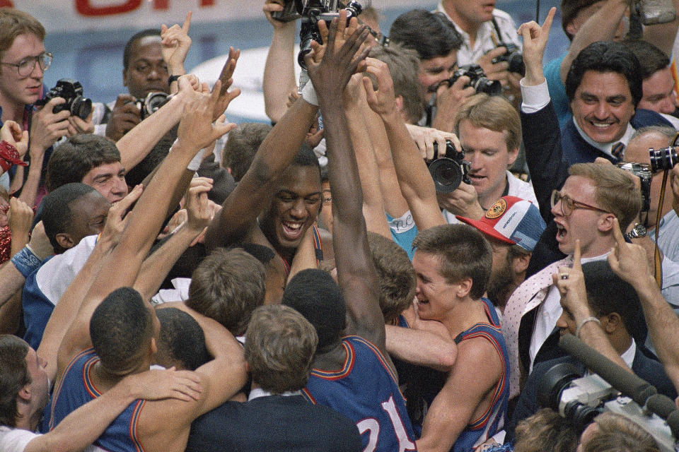 FILE - In this April 4, 1988, file photo Kansas' Danny Manning, facing camera at center left, is mobbed by fans and teammates after he led his team to an 83-79 victory over Oklahoma in the championship game of the NCAA men's basketball Final Four in Kansas City, Mo. Manning orchestrated one of the biggest championship game upsets with his 31 points, 18 rebounds and five steals. (AP Photo/Susan Ragan, File)
