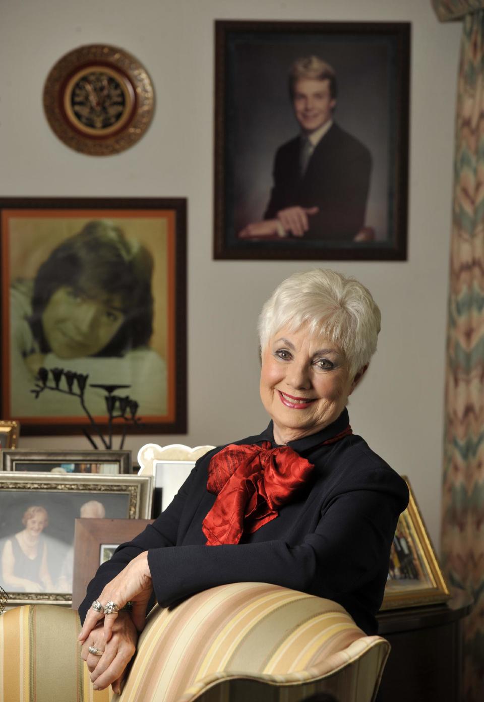 FILE - In this Monday, July 15, 2013 file photo, actress Shirley Jones poses for a portrait at her home in Los Angeles. Behind her are portraits of her stepson David Cassidy, left, and son Ryan Cassidy, top. Jones is celebrating her 80th birthday on the ground, instead of skydiving as she had planned. A spokesman for "The Partridge Family" actress said Monday, March 31, 2014, that Jones agreed to postpone the jump after her sons and grandchildren asked her to reconsider. (Photo by Chris Pizzello/Invision/AP, file)