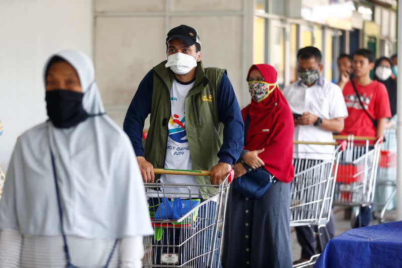 Consumers wearing protective face masks line up in front of a market amid the coronavirus disease (COVID-19) outbreak in Jakarta