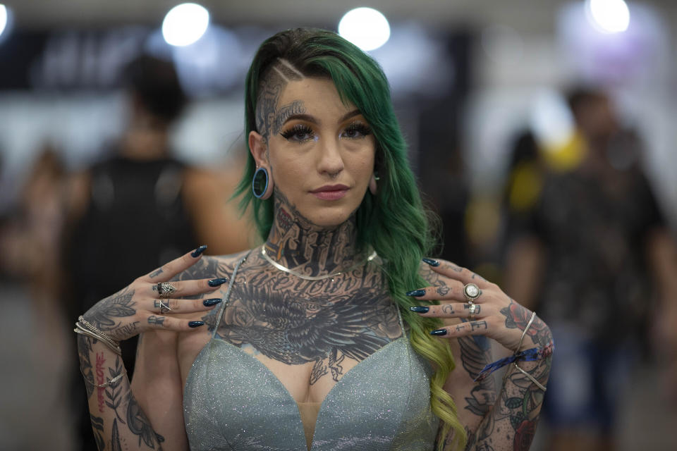 In this Oct. 25, 2019 photo, a woman stikes a pose as she shows off her tattoos during Tattoo Week, in Sao Paulo, Brazil. Tattoo Week is an annual event that attracts international tattoo and body piercing artists as well as consumers. (AP Photo/Andre Penner)