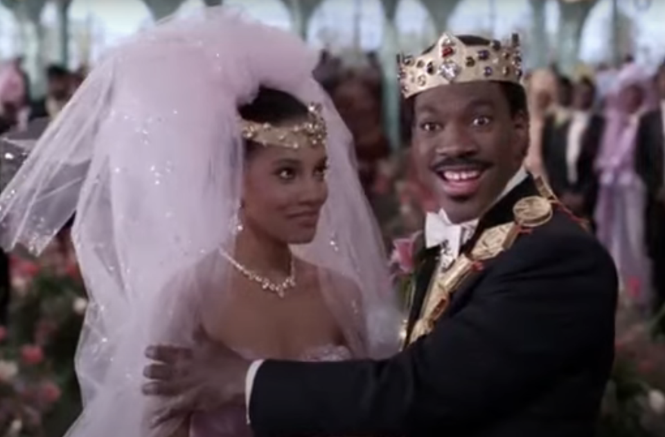 Eddie Murphy and Shari Headley dressed in royal wedding attire, with Eddie in a tuxedo and crown, and Shari in a bridal gown with a veil and headpiece