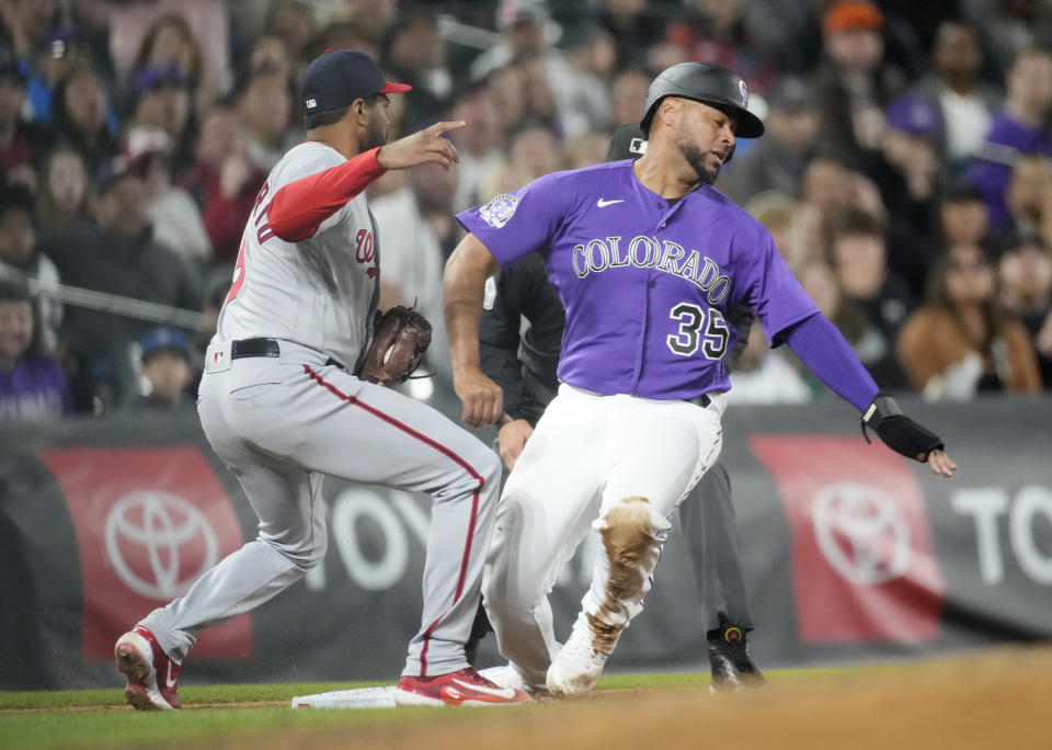 Washington Nationals third baseman Jeimer Candelario, left, fields a throw to put out Colorado Rockies' Elias Diaz, right, who was trying to reach third on a single hit by Yonathan Daza in the fourth inning of a baseball game Friday, April 7, 2023, in Denver. (AP Photo/David Zalubowski)