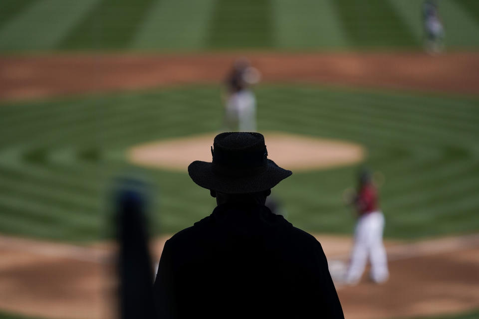 An usher is silhouetted while watching a spring baseball game between the Arizona Diamondbacks and the Milwaukee Brewers in Scottsdale, Ariz., Monday, March 1, 2021. (AP Photo/Jae C. Hong)