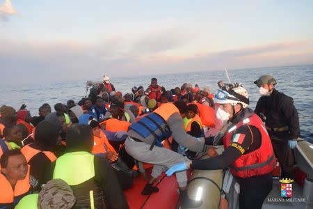 Migrants climb aboard a lifeboat during a rescue operation of 219 migrants by Italian naval vessel Bettica (not seen) in this February 23, 2016 handout photo provided by Marina Militare. REUTERS/Marina Militare/Handout via Reuters