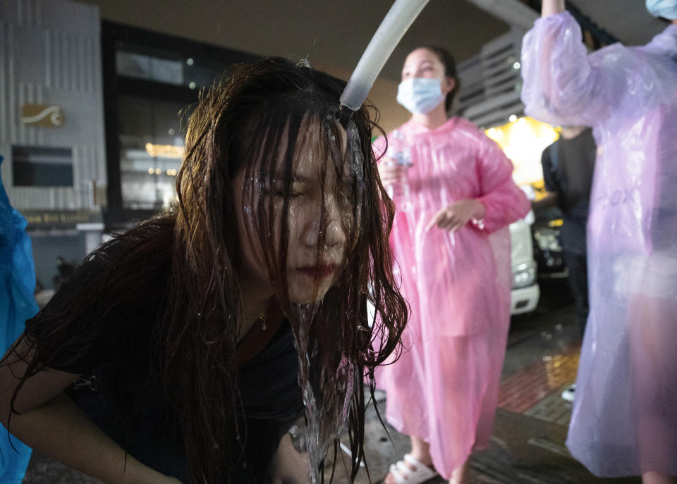 FILE - In this Oct. 16, 2020, file photo, a demonstrator washes her face after police water cannons dispersed them from a protest venue in Bangkok, Thailand. Fed up with an archaic educational system and enraged by the military's efforts to keep control over their nation, a student-led campaign has shaken Thailand’s ruling establishment with the most significant campaign for political change in years. (AP Photo/Sakchai Lalit, File)