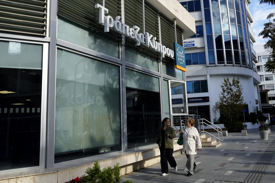 Women walk outside of a branch of "Bank of Cyprus" in central capital Nicosia, Cyprus, Wednesday, Jan. 24, 2024. Official figures show Cyprus making significant headway in weaning itself off Russian cash and business as it tries to clean up its image as a favorite destination for Moscow's money. According to the figures, the number of Russian clients using Cypriot banks has dropped 82% between 2014 up until the end of 2022. (AP Photo/Petros Karadjias)