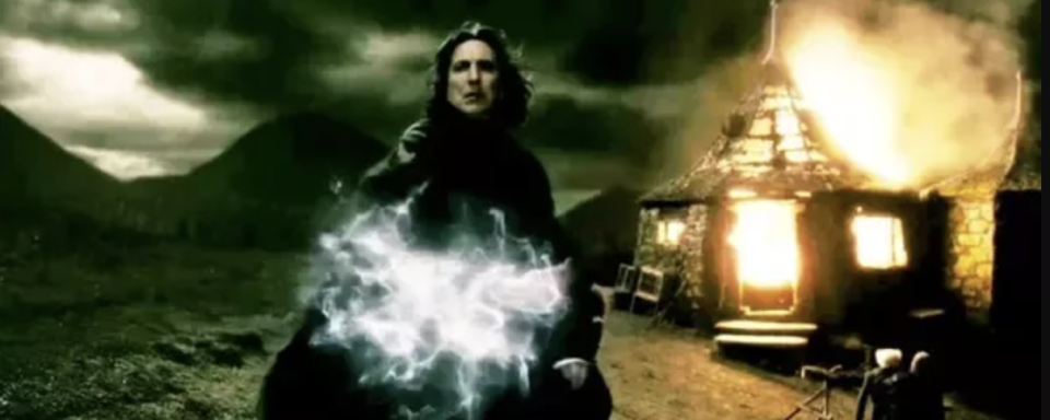 Snape standing in front of Hagrid's Hut, which is on fire, casting a spell