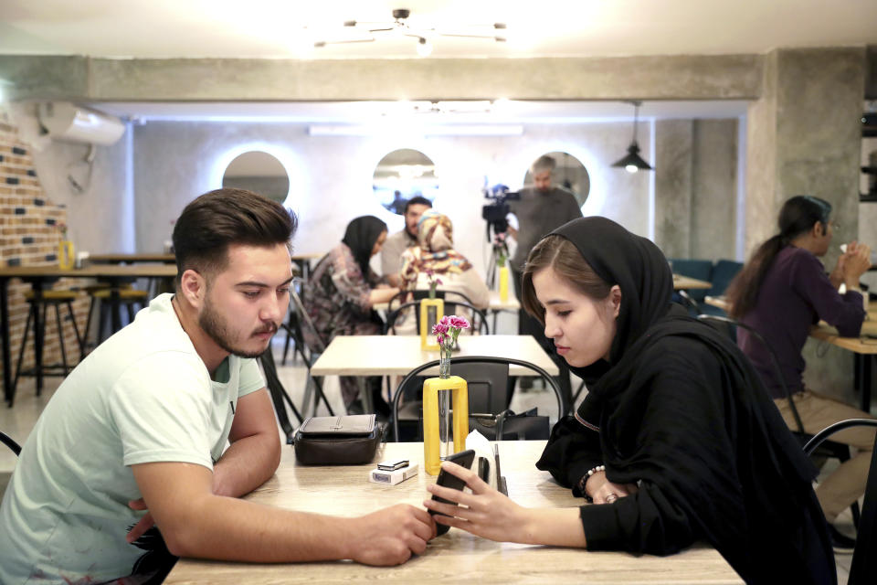 In this Monday, Oct. 7, 2019 photo, two Afghan refugees spend time at an Afghan cafe in downtown Tehran, Iran. More than 3 million Afghans including as many as 2 million who entered without legal permission, live in the Islamic Republic, according to United Nations estimates. Fatemeh Jafari, a 21-year-old Afghan refugee, hopes her Telma, or "Dream," Café in Tehran will help bridge the divides and xenophobia Afghans can face in Iran. (AP Photo/Ebrahim Noroozi)