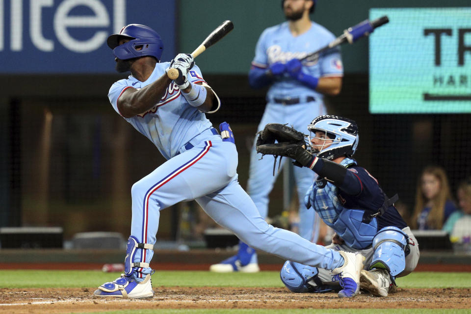 Texas Rangers Adolis Garcia, left, follows through on a solo home run in the sixth inning against the Minnesota Twins in a baseball game Sunday, June 20, 2021, in Arlington, Texas. (AP Photo/Richard W. Rodriguez)