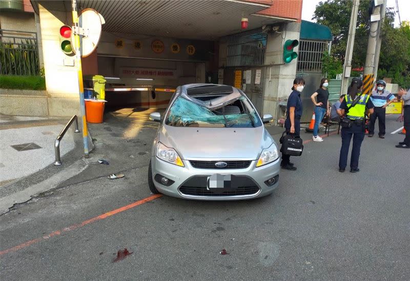 銀色轎車遭受撞擊，車頂凹陷呈現V字形，擋風玻璃整片碎裂，駕駛王姓男子受到極大驚嚇，墜樓女子則因為摔落車頂當緩衝，全身骨折住院治療中。(圖／翻攝畫面)