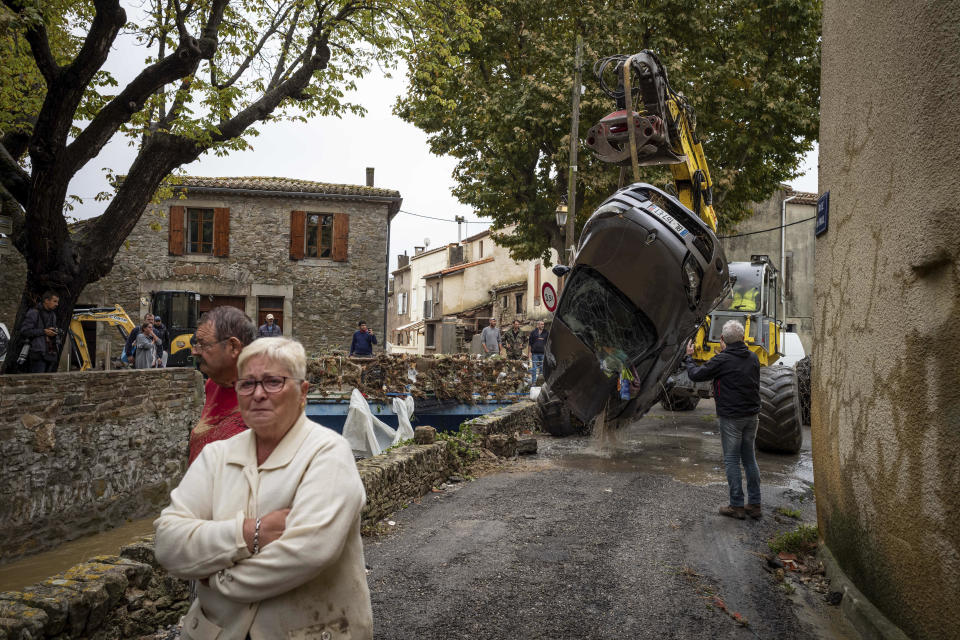 People react while residents pull a car out of a torrent after flash floods in the town of Villegailhenc, southern France, Monday, Oct.15, 2018. Flash floods tore through towns in southwest France, turning streams into raging torrents that authorities said killed several people and seriously injured at least five others. (AP Photo/Fred Lancelot)