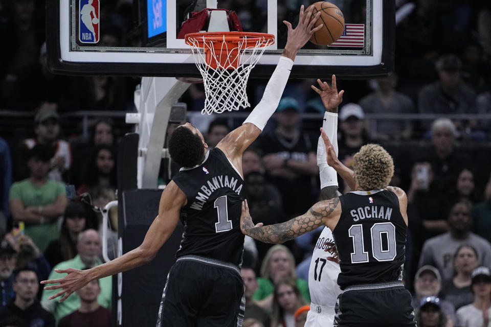 San Antonio Spurs center Victor Wembanyama (1) blocks a shot by Brooklyn Nets guard Dennis Schroder (17) during overtime of an NBA basketball game in Austin, Texas, Sunday, March 17, 2024. (AP Photo/Eric Gay)