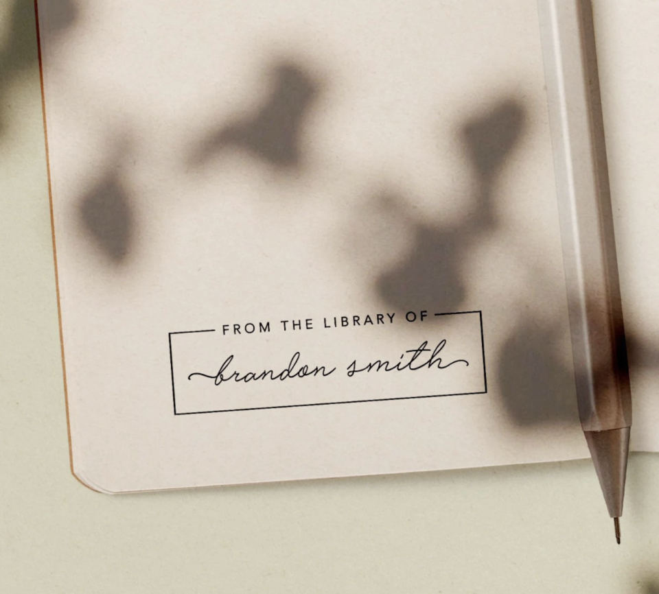 Custom Library Stamp on book with shadows and pencil (photo via Etsy)