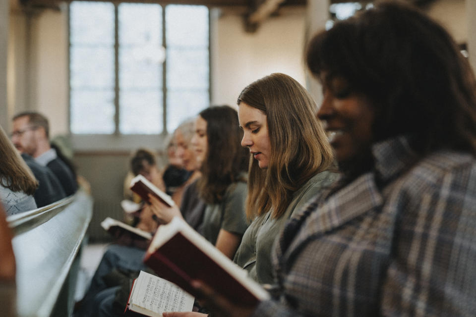 People reading books in what appears to be a communal setting, seated in rows, focused on their reading