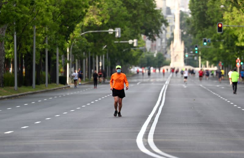 Un hombre con una mascarilla corre por el Paseo de la Castellana en Madrid