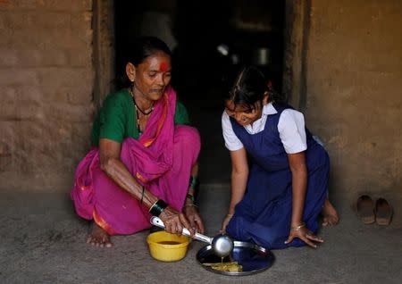 Drupada Pandurangkedar, 70, who studies at Aajibaichi Shaala (Grandmothers' School), serves her granddaughter Namita Thackrey lunch inside their house in Fangane village, India, February 15, 2017. REUTERS/Danish Siddiqui