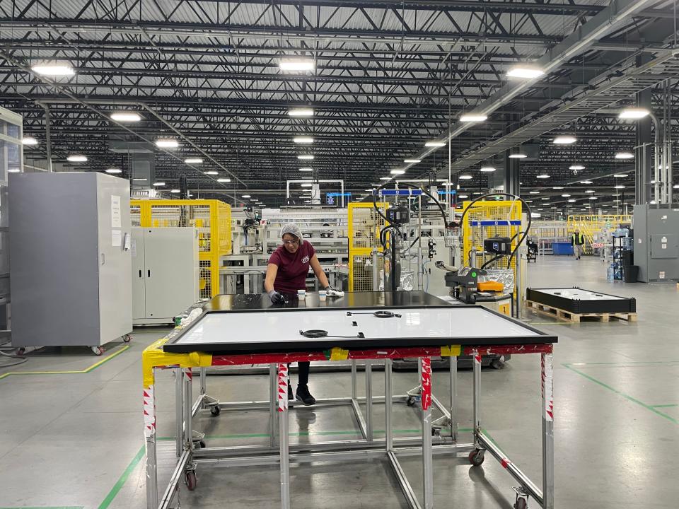 An employee at Qcells inspects a solar panel on the factory floor.