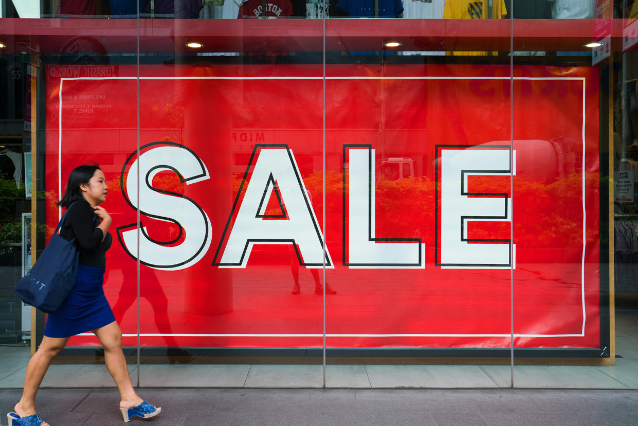 A woman walks past a sign advertising a sale displayed outside a store on Orchard Road in Singapore, on Sunday, June 3, 2018. (Photo: Nicky Loh/Bloomberg)
