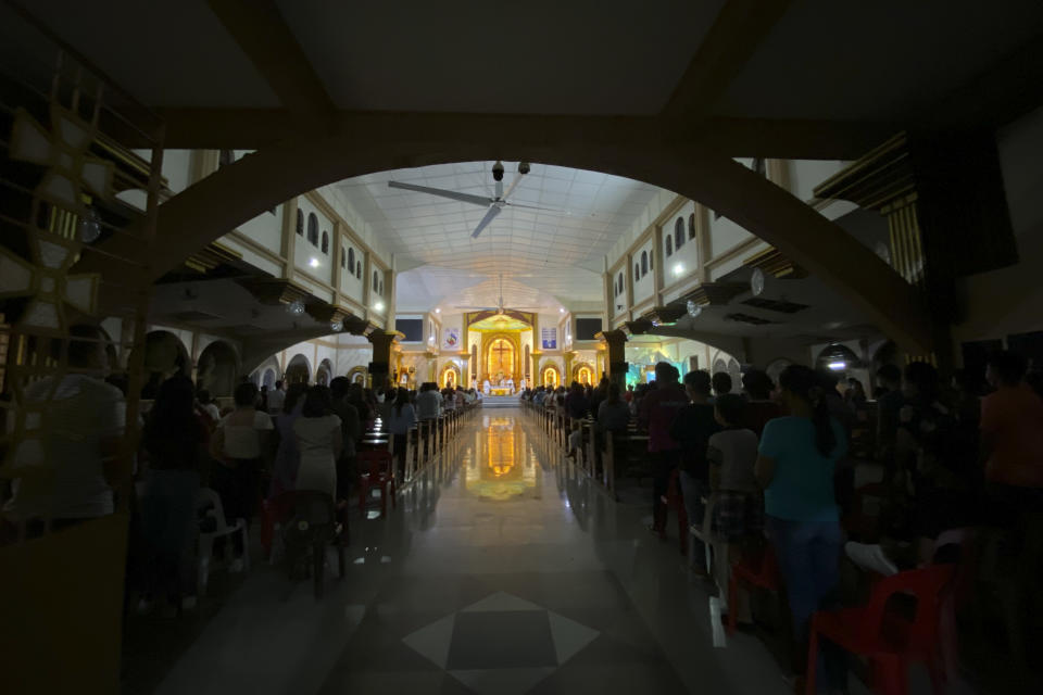 FILE - Residents attend a dimly-lit Christmas eve mass at the damaged San Nicolas de Tolentino Cathedral at typhoon-hit Surigao del Norte province, southern Philippines on Dec. 24, 2021. Caseloads of omicron have remained relatively low in many countries in Asia. For now, many remain insulated from the worst, although the next few months will remain critical. (AP Photo/Erwin Mascarinas, File)