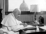 FILE - In this April 15, 1963 file photo, Pope John XXIII sits at his working desk in his studio in a IX century tower in the Vatican gardens. In background the dome of St. Peter's Basilica. The Pontiff found the tower - once a fortress and later the Vatican observatory - abandoned and in decay. He liked it, particularly for the beautiful view from its covered terrace, embracing a great part of Rome and the surrounding country, in clear weather as far as the sea, distant about 25 kilometers (16 miles). He had it repaired and spends many days working in the studio he has had arranged there. While much of the focus of Sunday's dual canonization will be on Pope John Paul II's globe-trotting, 26-year papacy and his near-record sprint to sainthood, many older Catholics will be celebrating the short but historic pontificate of the "Good Pope," John XXIII. (AP Photo/Luigi Felici, File)