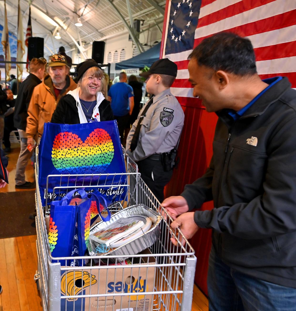 Sandra Briggs of Millbury and her partner Vietnam War U.S. Army veteran and Purple Heart recipient John Grady, 79, are offered a hand out to their car by Avient Corp. volunteer Sumendra Shrestha during Veterans Inc. annual Holiday Harvest Tuesday.