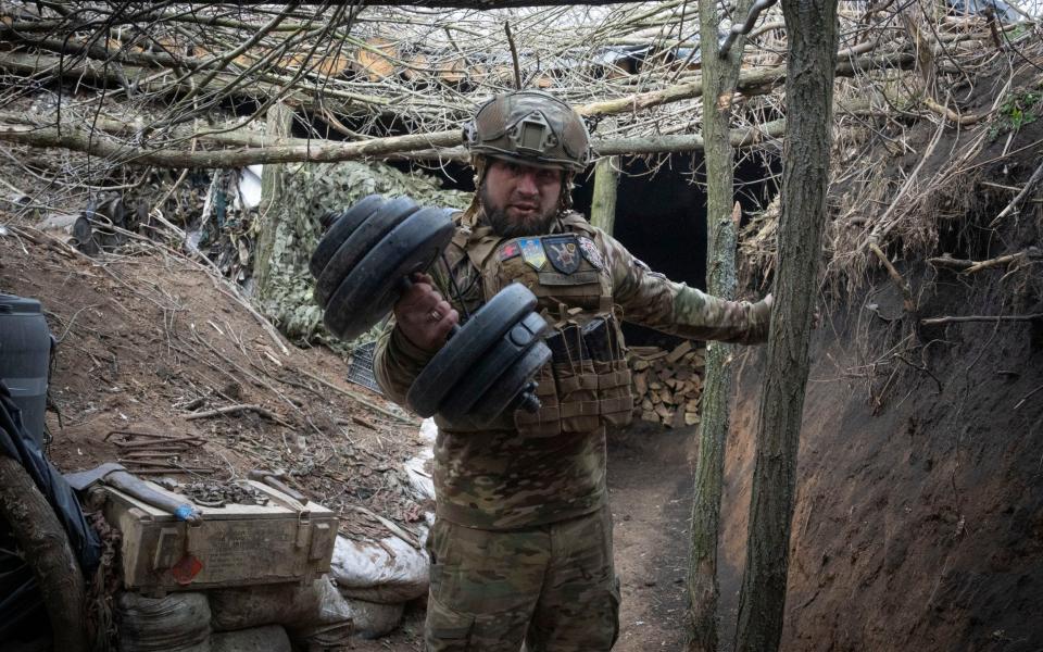 A Ukrainian serviceman of the 28th Separate Mechanised Brigade shows his dumbbells in a trench at the front line