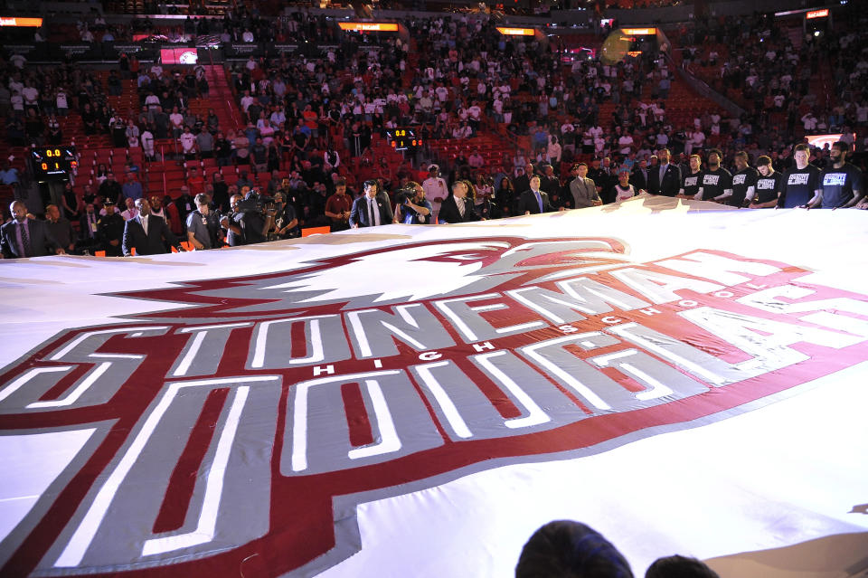 A large banner in memory of the victims of the Marjory Stoneman Douglas High School shooting is unfurled before an NBA basketball game in Miami on Saturday, Feb. 24, 2018, between the Miami Heat and the Memphis Grizzlies. (AP Photo/Gaston De Cardenas)