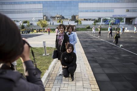 Girls take pictures of themselves at a park in front of the Pothonggang Department Store in central Pyongyang October 11, 2015. Picture taken October 11, 2015. REUTERS/Damir Sagolj