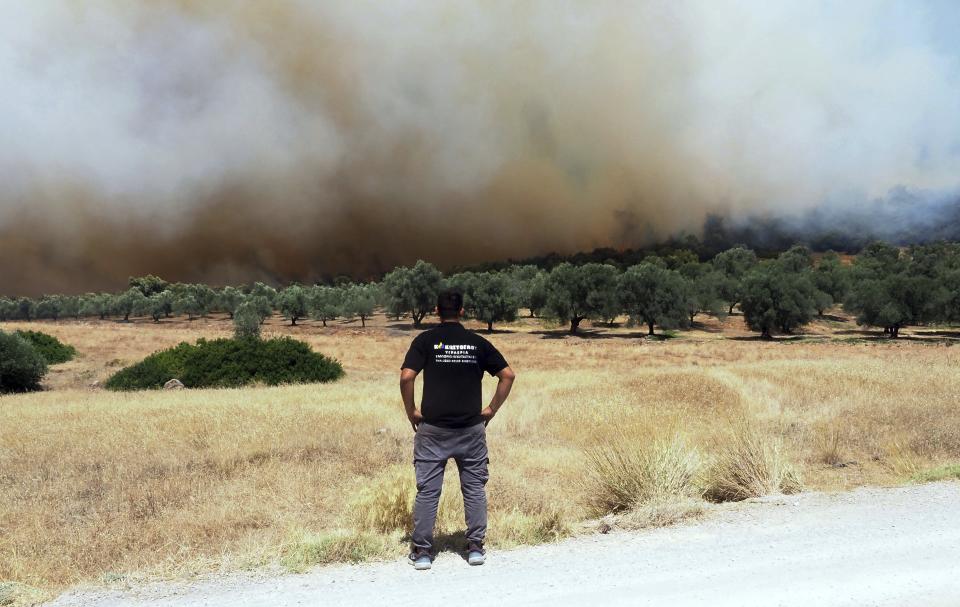 A man watches the wildfire burning near Vatontas village on the Aegean Sea island of Evia, Greece, Monday, Aug. 21, 2023. Major wildfires were burning in Greece and on one of Spain's Canary Islands off the African coast Monday, with hot, dry and windy conditions hampering the efforts of hundreds of firefighters battling the blazes, two of which have been burning for several days. (AP Photo/Thodoris Nikolaou)