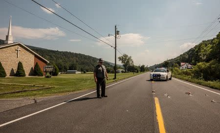 A Pennsylvania State Trooper restricts access to an area where a CSX Corp freight train carrying flammable materials derailed as it moved through Hyndman, Pennsylvania, U.S., August 2, 2017. REUTERS/Maranie Staab