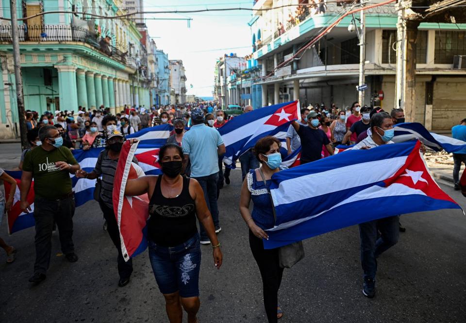 People march down the streets of Havana holding Cuban flags