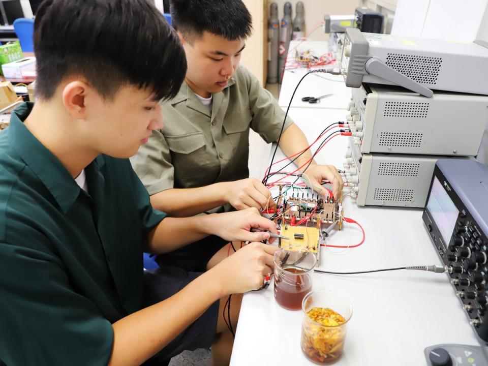 嘉大電機工程學系大學部學生楊書桓(右)及吳翊誠在教授跨域指導下研發出二氧化硫濃度偵測器。（圖：嘉義大學提供）