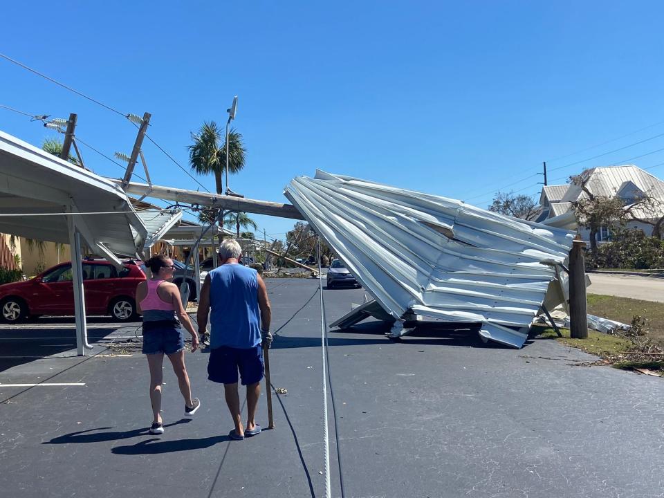 Two residents at Ballynahinch Condominiums in Cape Coral strolled across their once-flooded parking lot to clean up debris.