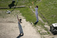 Greek actress Xanthi Georgiou, left, playing the role of the High Priestess, releases a dove as Greek shooting Olympic champion Anna Korakaki, the first torchbearer, holds the torch of the 2020 Tokyo Olympic Games during the flame lighting ceremony at the closed Ancient Olympia site, birthplace of the ancient Olympics in southern Greece, Thursday, March 12, 2020, 2020. Greek Olympic officials are holding a pared-down flame-lighting ceremony for the Tokyo Games due to concerns over the spread of the coronavirus. Both Wednesday's dress rehearsal and Thursday's lighting ceremony are closed to the public, while organizers have slashed the number of officials from the International Olympic Committee and the Tokyo Organizing Committee, as well as journalists at the flame-lighting. (AP Photo/Yorgos Karahalis)