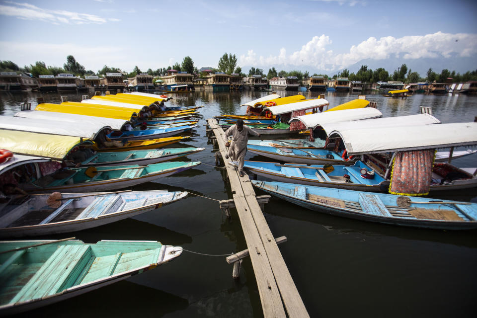 A Kashmiri boatman walks near anchored boats at Srinagar, Indian controlled Kashmir on Aug. 2, 2021. From the Great Wall to the picturesque Kashmir valley, Asia's tourist destinations are looking to domestic visitors to get them through the COVID-19 pandemic's second year. (AP Photo/Mukhtar Khan)