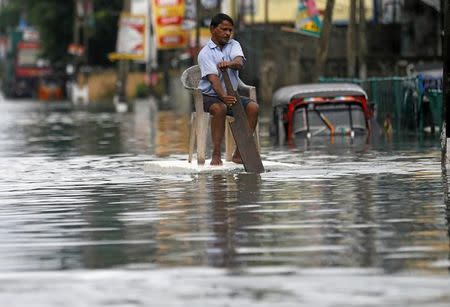 A man sits on a chair as he uses a piece of styrofoam to move through a flooded road in Wellampitiya, Sri Lanka May 21, 2016. REUTERS/Dinuka Liyanawatte