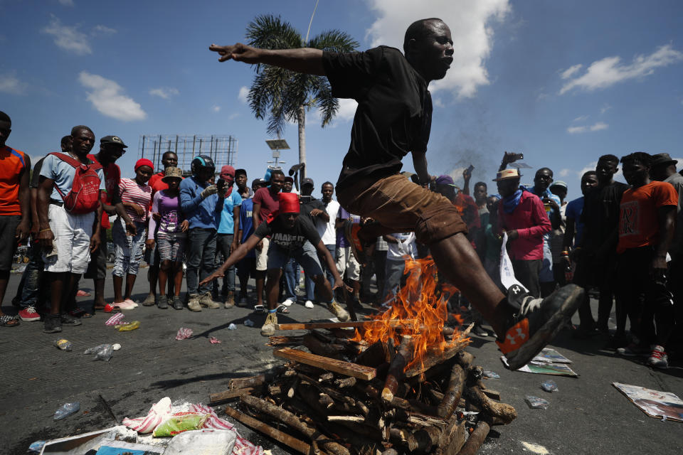 A man jumps over a fire during a voodoo ceremony to grant protection to the people, as protesters calling for the resignation of President Jovenel Moise gathered at a bridge in the Delmar area of Port-au-Prince, Haiti, Thursday, Oct. 17, 2019. Haiti's embattled president was forced on Thursday to hold a private ceremony amid heavy security for what is usually a public celebration of one of the country's founding fathers, revolution leader Jean-Jacques Dessalines. (AP Photo/Rebecca Blackwell)