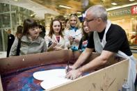 People watch British artist Damien Hirst produce a piece of work in the Pinchuk Art Center in Kiev April 23, 2009.