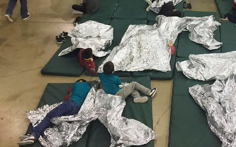 Children who've been taken into custody related to cases of illegal entry into the United States, rest in one of the cages at a facility in McAllen, Texas - Credit: AP