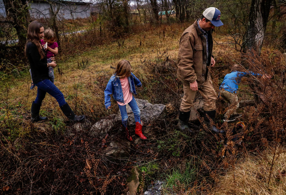 The Kennedy family cross a stream on their property while on a hike at their home in Columbia, Tenn. on Nov. 29, 2022. 