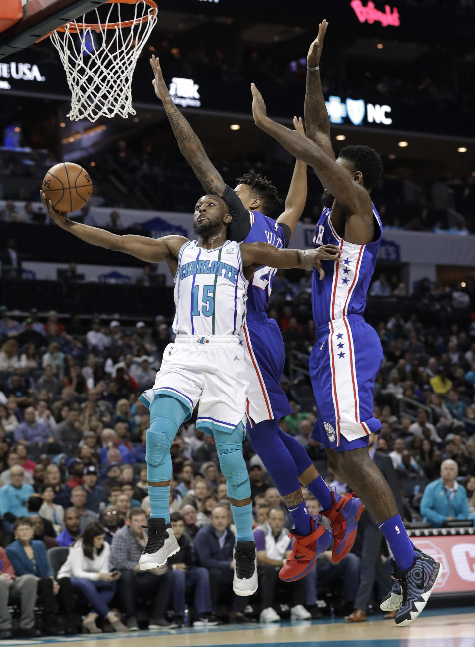 Charlotte Hornets' Kemba Walker, left, drives past Philadelphia 76ers' Jimmy Butler, back, and Joel Embiid during the first half of an NBA basketball game in Charlotte, N.C., Saturday, Nov. 17, 2018. (AP Photo/Chuck Burton)