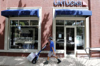 A delivery driver pushes a cart past an Untuckit men's clothes store in Dallas, Tuesday, July 7, 2020. Some big corporate names are on the government's list of 650,000 recipients of coronavirus relief loans despite the controversy that prompted other high-profile businesses to return billions of dollars in loan. Untuckit, which has 85 shirt stores, received a loan between $5 million and $10 million; the company said it used the money to keep paying its workers. (AP Photo/LM Otero)